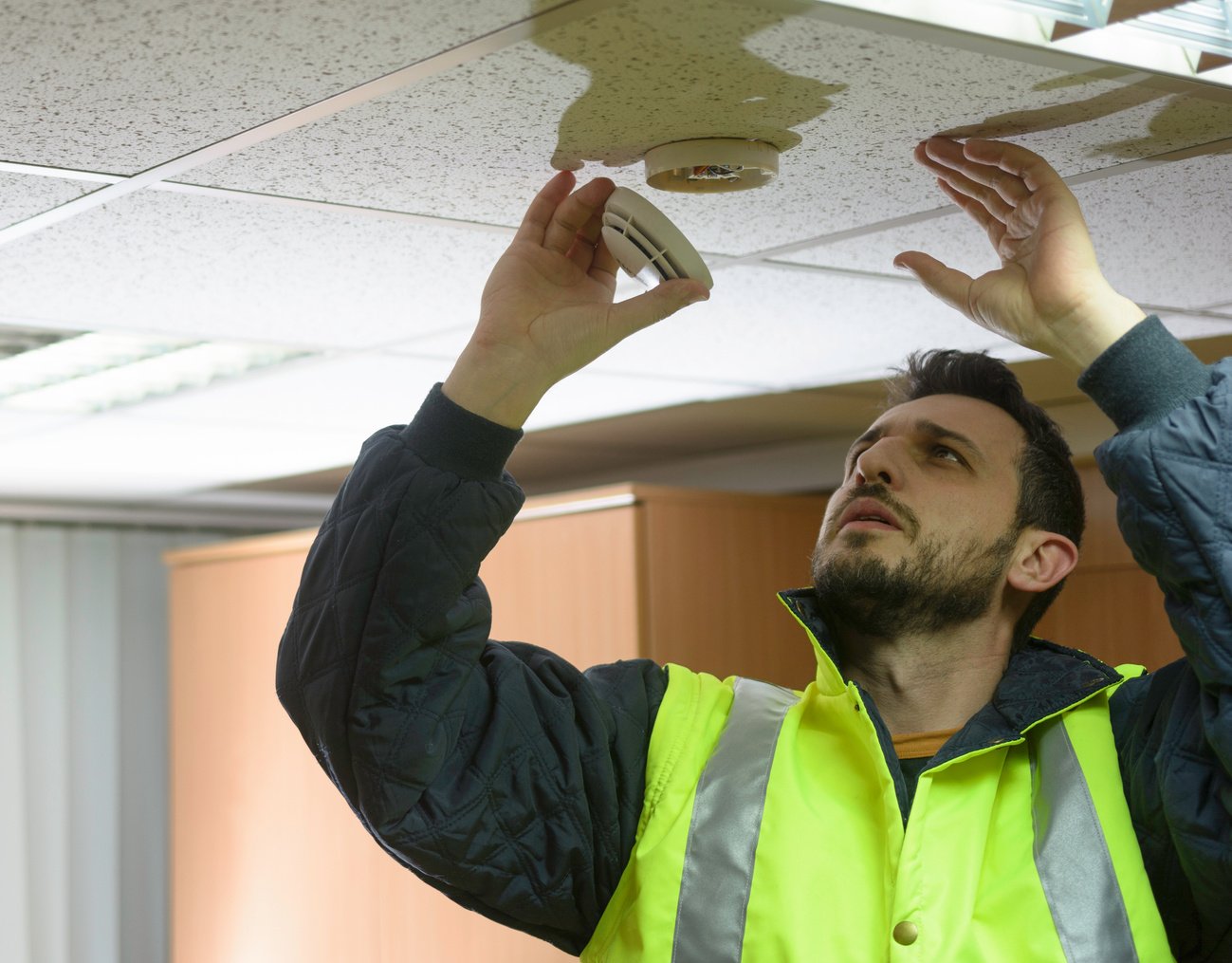 Firefighter testing a smoke detector fire alarm